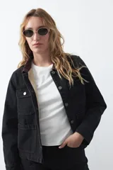 Campera de jean color negro con cuello de pana en tono marrón, cierre frontal con botones metálicos y bolsillos frontales tipo cargo.