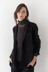 Blazer negro de terciopelo con forro animal print, hombreras y bolsillos frontales.