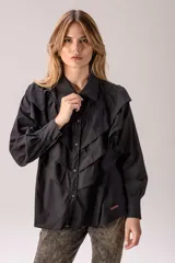 Camisa blanca de corte clásico con volados frontales y en los hombros, manga larga con puños abotonados y cierre frontal con botones.