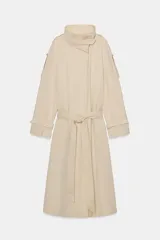 Trench de algodón con cuello alto, manga larga ajustable con trabillas y cierre frontal con botones ocultos. Presenta trabillas en los hombros, bolsillos laterales ocultos y cinturón ajustable en la cintura.