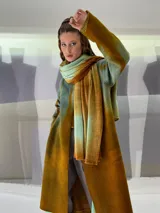 Tapado largo de fieltro de lana merino con teñido artesanal tie-dye en degradé de azul. Tiene cuello alto, cierre lateral con broches ocultos, bolsillos laterales y corte amplio.