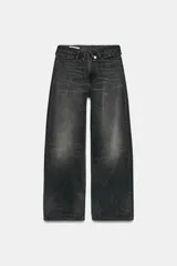 Jeans de mezclilla de tiro medio, corte wide leg y diseño relaxed. Presenta detalles rotos y desgastados en las piernas, y una cinturilla doblada superpuesta con trabillas y cierre frontal con cremallera y botón metálico.