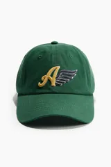 Gorra de sarga de algodón color verde, con diseño de seis paneles y visera curva. Presenta un bordado frontal con la letra A en color dorado y un ala en color azul oscuro. Incluye cinta antitranspirante interna y cierre metálico ajustable en la parte posterior.