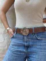 Cinturón de cuero color tostado con hebilla metálica plateada en forma de escudo de Uruguay.