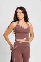 Conjunto deportivo compuesto por un top de escote redondo con breteles anchos y una calza larga de tiro alto. Ambas prendas son de color marrón con detalles de costuras blancas a contratono y el logo bk. estampado en el frente del top.