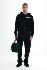 Campera con capucha negra, de corte holgado (boxy), con cierre bidireccional y bolsillos canguro delanteros.