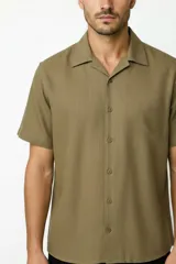 Camisa de manga corta color verde militar, con cuello camisero y cierre frontal de botones.