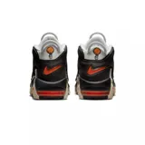 Championes Nike Air More Uptempo 96 de color blanco, negro y gris, con detalles en naranja y rojo. Presentan el característico diseño con las letras "AIR" sobredimensionadas en los laterales, suela de goma con amortiguación visible y un estilo urbano robusto.