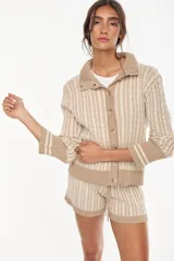 Cardigan de punto con patrón trenzado, color crudo y visón, con cuello solapa, cierre frontal de botones y mangas largas con puños elásticos rayados.