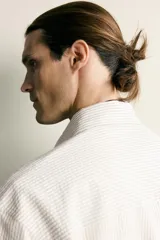 Camisa relaxed fit de algodón con estructura, cuello solapa, manga larga con puño abotonado, bolsillo de parche en el pecho y cierre frontal con botones. Presenta diseño de rayas finas.