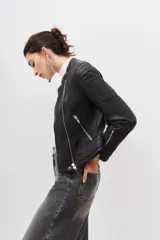 Campera de cuero ovino color negro, con cierre frontal asimétrico, cuello redondo con broche a presión y cierres metálicos en los puños.