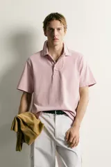 Polo de corte regular fit en color rosado con efecto lavado. Presenta cuello solapa, cierre frontal de botones y mangas cortas con acabados en rib.