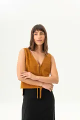 Chaleco de gamuza color mostaza, con escote en V y cierre frontal con lazos.