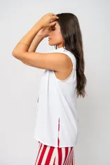Camisa blanca sin mangas con cuello mao adornado con un delicado volado y cierre frontal con botones.