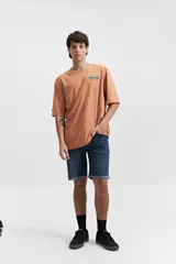 Remera verde esmeralda de manga corta con calce oversize, cuello redondo y estampado frontal con texto en azul.