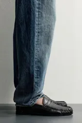 Mocasín de vestir negro confeccionado en piel, con detalle fruncido en la parte delantera y antifaz en el empeine. Cuenta con suela a tono y ligero tacón.