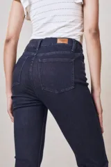 Pantalón de jean azul oscuro, tiro alto, corte ajustado en la cadera y muslos, y acampanado desde la rodilla.