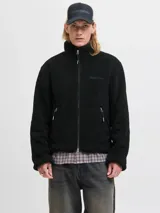 Campera tipo teddy de cuello alto y manga larga, confeccionada en tejido de textura suave. Presenta cierre frontal completo, bolsillos laterales con cierre y un pequeño bordado en el pecho.