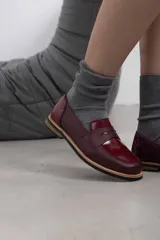 Mocasín de cuero vacuno en color marrón, con diseño bitono que combina texturas lisas y con grabado tipo cocodrilo en el empeine. Cuenta con detalle de estribo clásico y suela plana con vira en contraste.