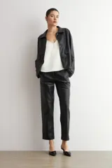 Chaqueta de eco cuero negro con cuello camisero, cierre frontal oculto y mangas largas con puños rectos.