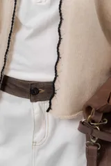 Saco básico de punto color marfil, confeccionado en lambswool, con corte entallado tipo chaquetita. Destaca por detalles de blonda tejida en los puños y a lo largo de la abertura frontal, con bordes en color contrastante.
