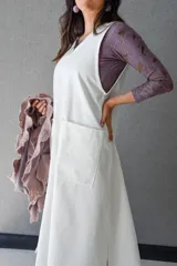 Vestido blanco de gabardina de algodón, corte evasé, sin mangas, con cuello redondo y bolsillo delantero.