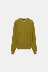 Jersey de punto fino con cuello redondo y manga larga con puños elásticos. Presenta un diseño minimalista con costuras visibles en los hombros.