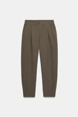 Pantalón de tiro medio con pinzas delanteras, bolsillos laterales y falsos bolsillos traseros. Presenta un corte holgado que se estrecha hacia el tobillo, con bajo acabado en pliegues y cierre frontal con cremallera, botón y gancho.