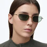 Lentes de sol con montura metálica dorada y lentes rectangulares de color verde oscuro. Diseño minimalista y ligero con terminaciones en acetato.