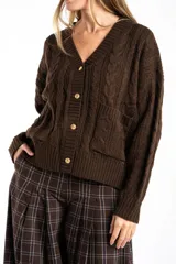 Cardigan de punto con diseño de trenzas, color marrón oscuro, con escote en V, cierre frontal de botones dorados y bolsillos delanteros.