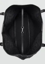 Bolso tipo tote negro confeccionado en cuero con diseño trenzado, asas largas para el hombro y cierre de botón magnético.