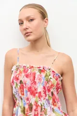 Top de tirantes finos con escote recto y detalle fruncido con elástico en el pecho. Presenta diseño con volados escalonados y estampado floral color rosado.
