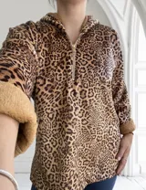 Buzo con capucha y cierre parcial con cremallera, de color marrón con estampado animal print y puños de piel sintética.