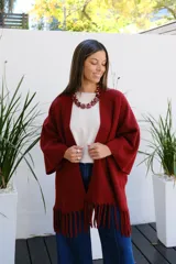Saco abierto tipo capa en color bordó, confeccionado en tejido de punto suave, con mangas amplias y detalle de flecos en el ruedo.