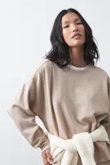 Buzo de manga larga color marrón chocolate, con silueta relajada, hombros caídos y diseño minimalista. Confeccionado en tejido suave con caída fluida.