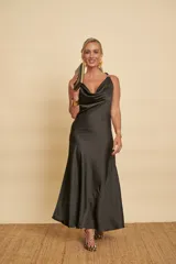 Vestido largo negro de satén, con escote drapeado, tirantes finos con detalle de argollas doradas y falda de corte evasé.