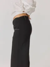 Pantalón de corte relajado color marrón oscuro, con costuras en hilo rojo a contraste y bordado decorativo en el bolsillo delantero.