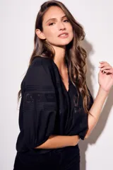 Blusa negra de algodón peinado con calce oversize, escote en V, mangas tres cuartos abullonadas y detalles de encaje y bordados en el frente y mangas.