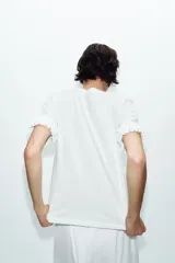 Camiseta de cuello redondo confeccionada en algodón, con mangas cortas decoradas con volantes en el mismo tejido y bajo recto.