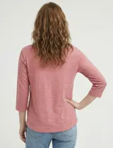 Blusa de manga tres cuartos color rosado, confeccionada en modal texturizado. Presenta un escote en V con cuello a la base y apliques nacarados en el área del escote.