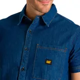 Camisa de manga corta confeccionada en tejido denim azul, con cuello camisero, cierre frontal de botones y bolsillo en el pecho con etiqueta de la marca CAT.