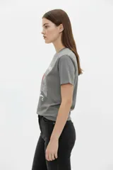 Remera de algodón negra de manga corta y cuello redondo, con estampa frontal que incluye letras rojas y gráficos en tonos dorados.