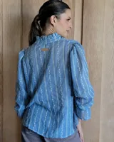 Blusa de algodón con cuello mao y volados, mangas largas con puños elásticos y corte holgado.