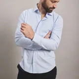 Camisa de vestir negra de manga larga, confeccionada en tejido técnico elástico y libre de arrugas, con cuello clásico y cierre frontal de botones.