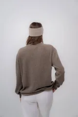 Vincha de lana color beige, tejida a mano, con diseño trenzado en el frente.