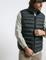 Chaleco acolchado de diseño capitoneado con cierre frontal al tono, cuello alto y ribetes en sisas y ruedo.