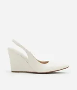 Zapato blanco de punta fina con taco alto tipo anabela (cuña) y tira elástica tipo slingback en el talón.