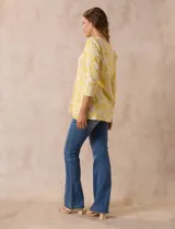 Blusa amarilla estampada con motivos florales en blanco, escote en V y mangas tres cuartos.