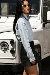 Minifalda negra de cuero con costuras horizontales y tres hebillas metálicas plateadas en el lateral.