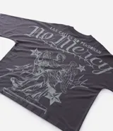 Remera de corte oversized color gris oscuro, con cuello redondo y manga corta. Presenta una estampa gráfica en la espalda que incluye un ángel, estrellas y el lettering 'No Mercy' junto a la frase 'Las calles no perdonan'.